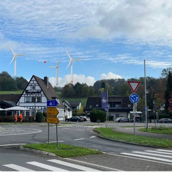 Fotocollage: Ein Kreisverkehr, dahinter ein Fachwerkhaus, am Horizont drei Windräder.