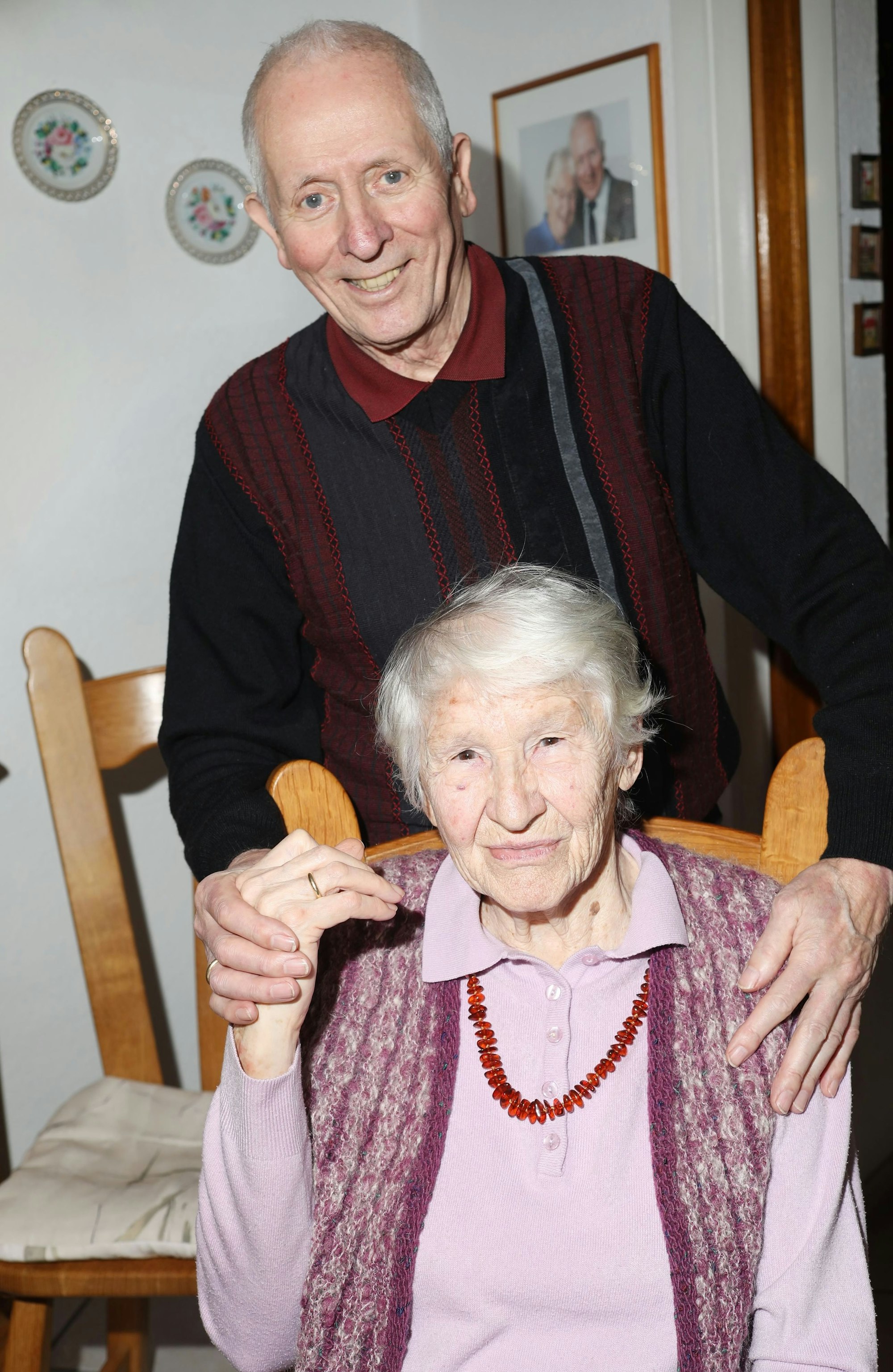 Peter und Irmgard sind im Doppelporträt zu sehen, er steht hinter ihr, sie sitzt auf einem Stuhl und hält seine Hand.