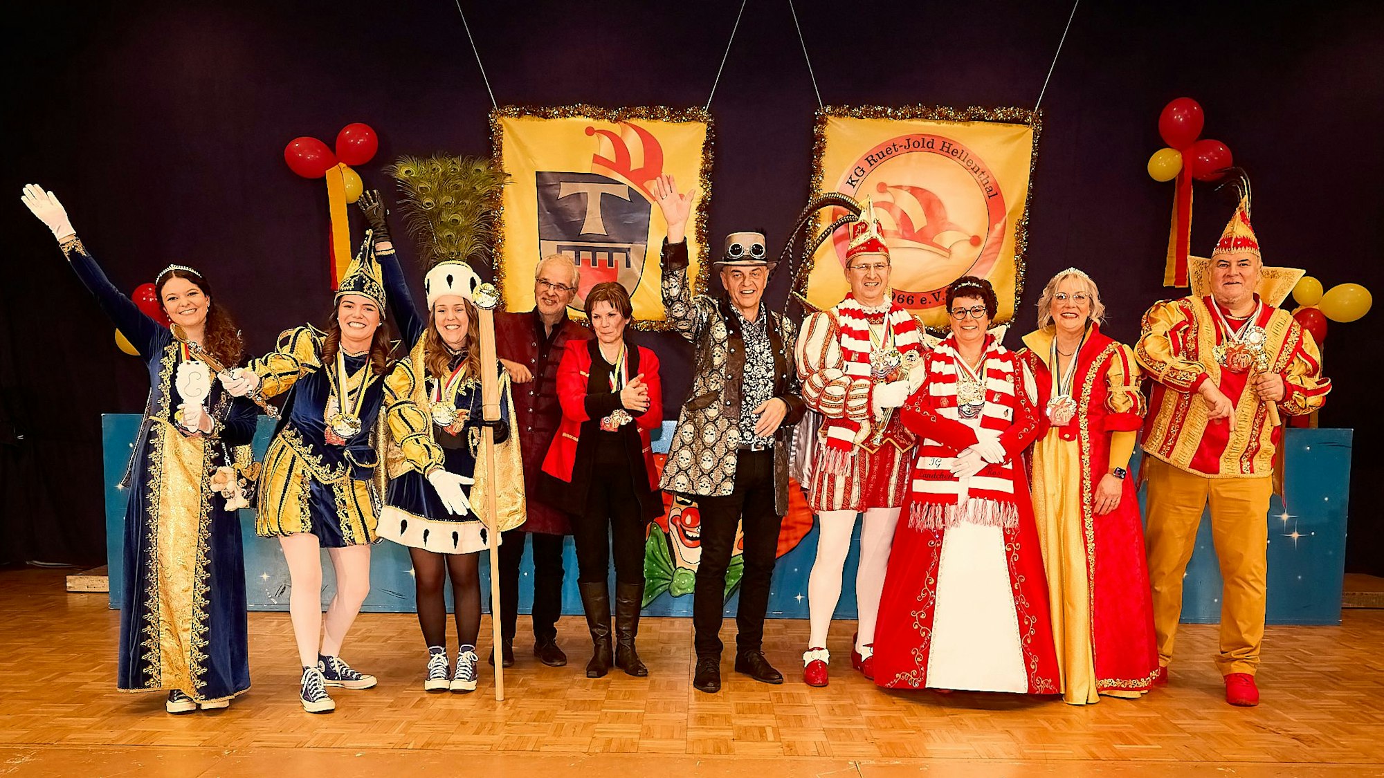 Eine Gruppe Menschen, teilweise im Ornat der Tollitäten, steht auf der Bühne und winkt.