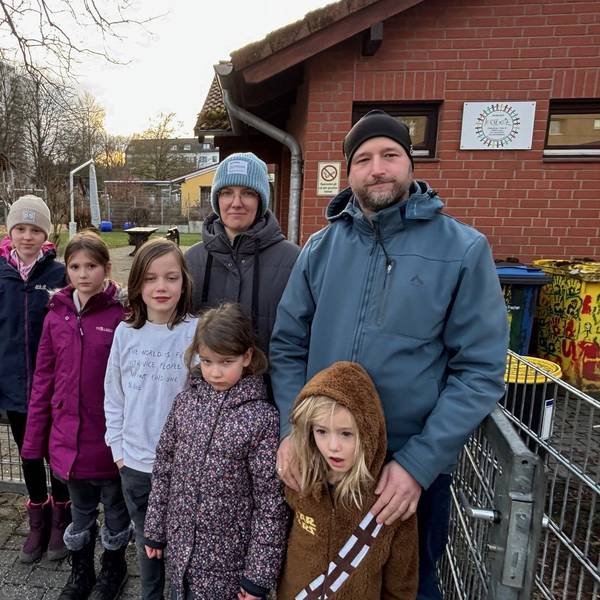 Eine Frau, ein Mann und Kinder stehen vor dem Hort, der geschlossen werden soll.