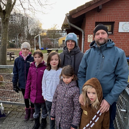 Eine Frau, ein Mann und Kinder stehen vor dem Hort, der geschlossen werden soll.