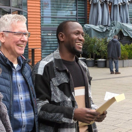 Drei Menschen freuen sich auf einem Platz.