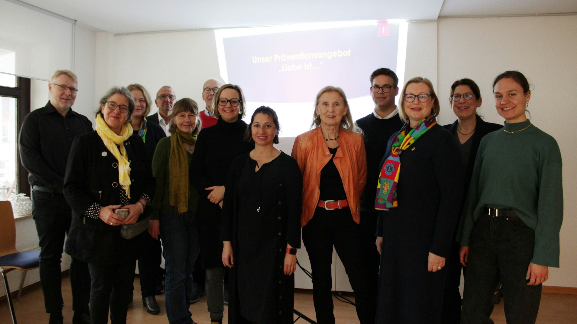 Männer und Frauen stehen vor einer Beamer-Projektion.
