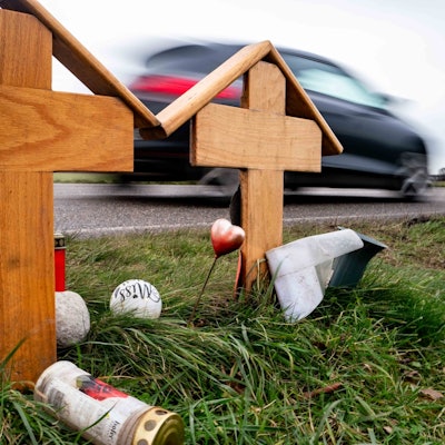 Zwei Holzkreuze erinnern an den Unfall zwischen Weilerswist und Metternich am Karnevalssonntag des vergangenen Jahres. Ein schwarzes Auto fährt auf der Straße daran vorbei.