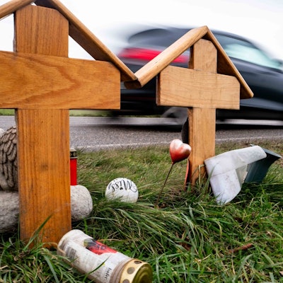 Das Bild zeigt zwei Holzkreuze an der L163. Im Hintergrund fährt ein Auto vorbei.