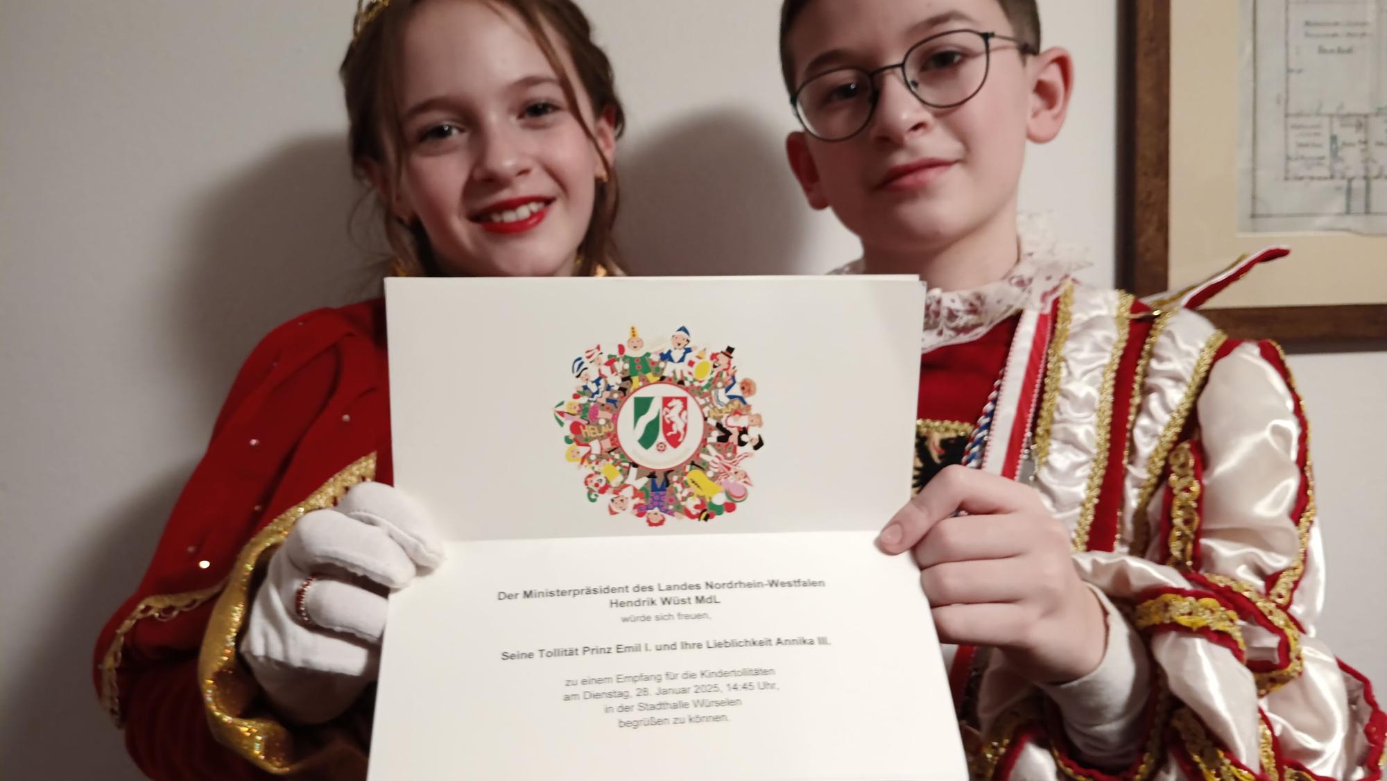 Das Kaller Kinderprinzenpaar Prinz Emil (Sträußl) und Prinzessin Annika (Pleuß) hält eine Einladung zum Empfang von Ministerpräsident Hendrik Wüst in den Händen.