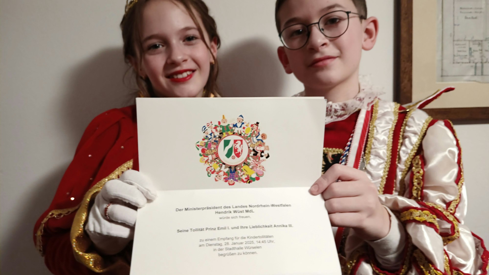 Das Kaller Kinderprinzenpaar Prinz Emil (Sträußl) und Prinzessin Annika (Pleuß) hält eine Einladung zum Empfang von Ministerpräsident Hendrik Wüst in den Händen.