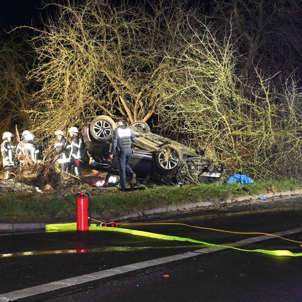 Das Bild zeigt mehrere Einsatzkräfte der Feuerwehr neben einem überschlagenen Pkw.
