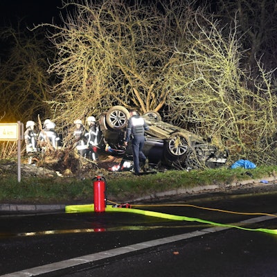 Das Bild zeigt mehrere Einsatzkräfte der Feuerwehr neben einem überschlagenen Pkw.