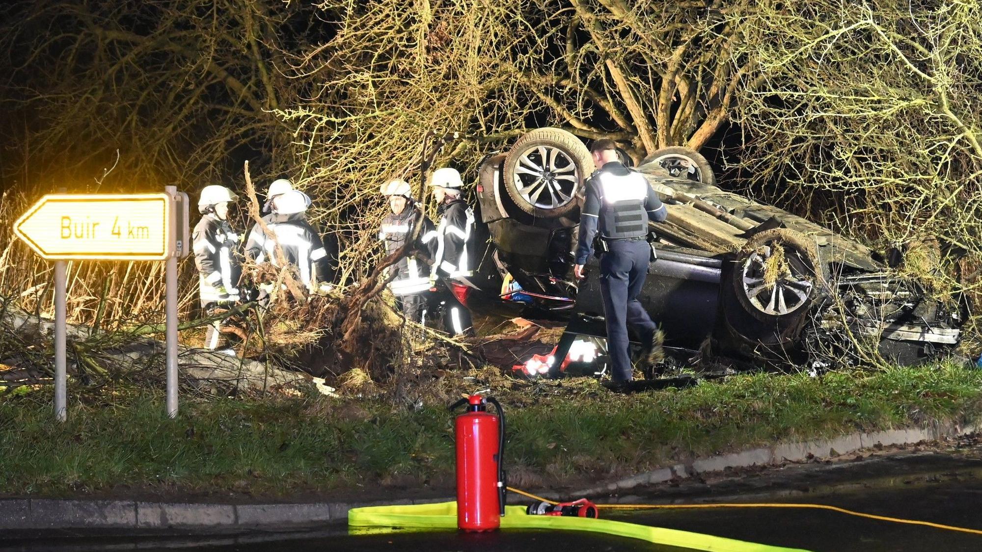 Das Bild zeigt mehrere Einsatzkräfte der Feuerwehr neben einem überschlagenen Pkw.