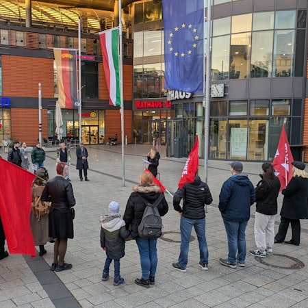 Menschen stehen mit Fahnen bei einer Protestveranstaltung vor dem Rathaus in Wiesdorf.