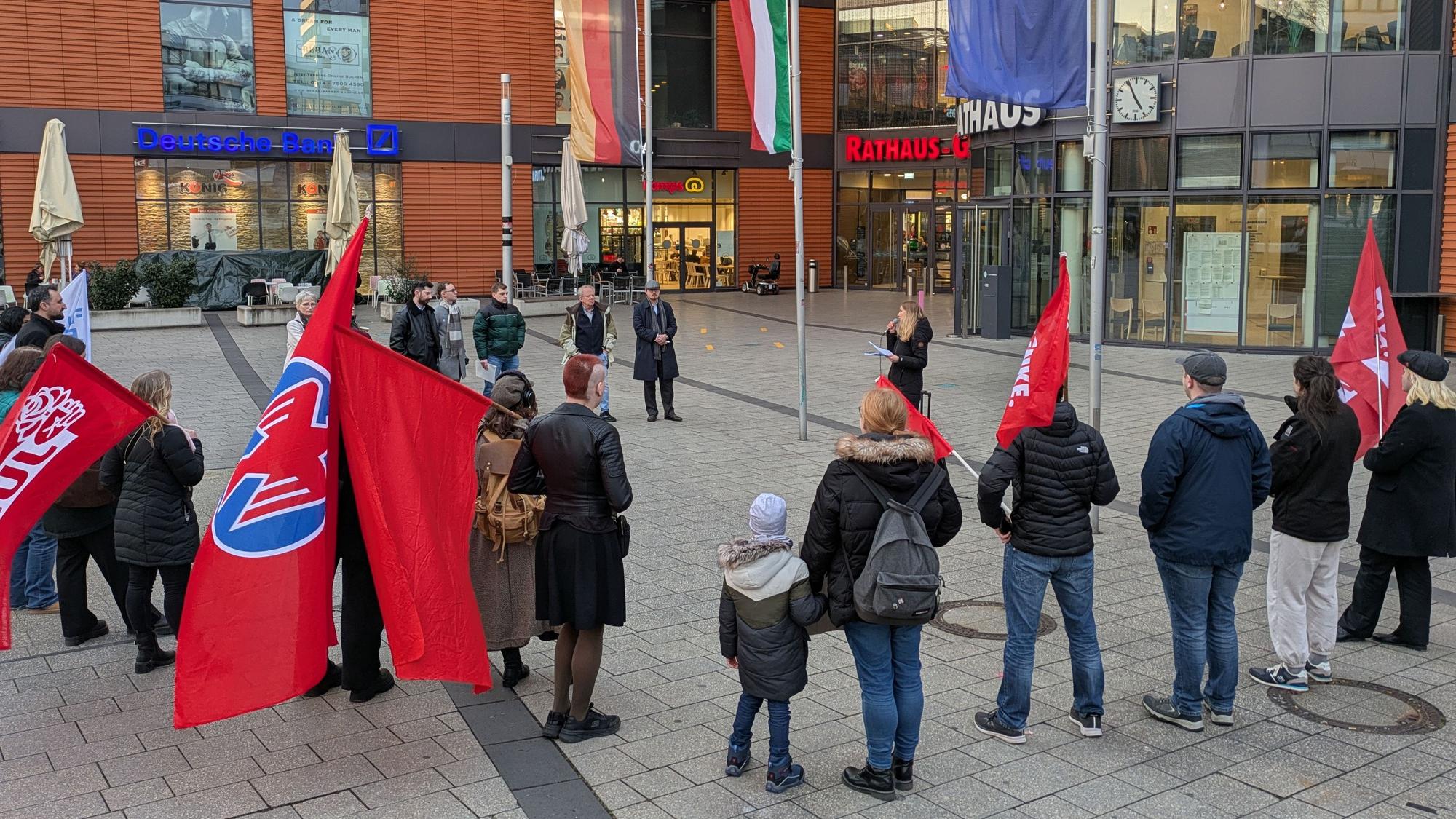 Menschen stehen mit Fahnen bei einer Protestveranstaltung vor dem Rathaus in Wiesdorf.