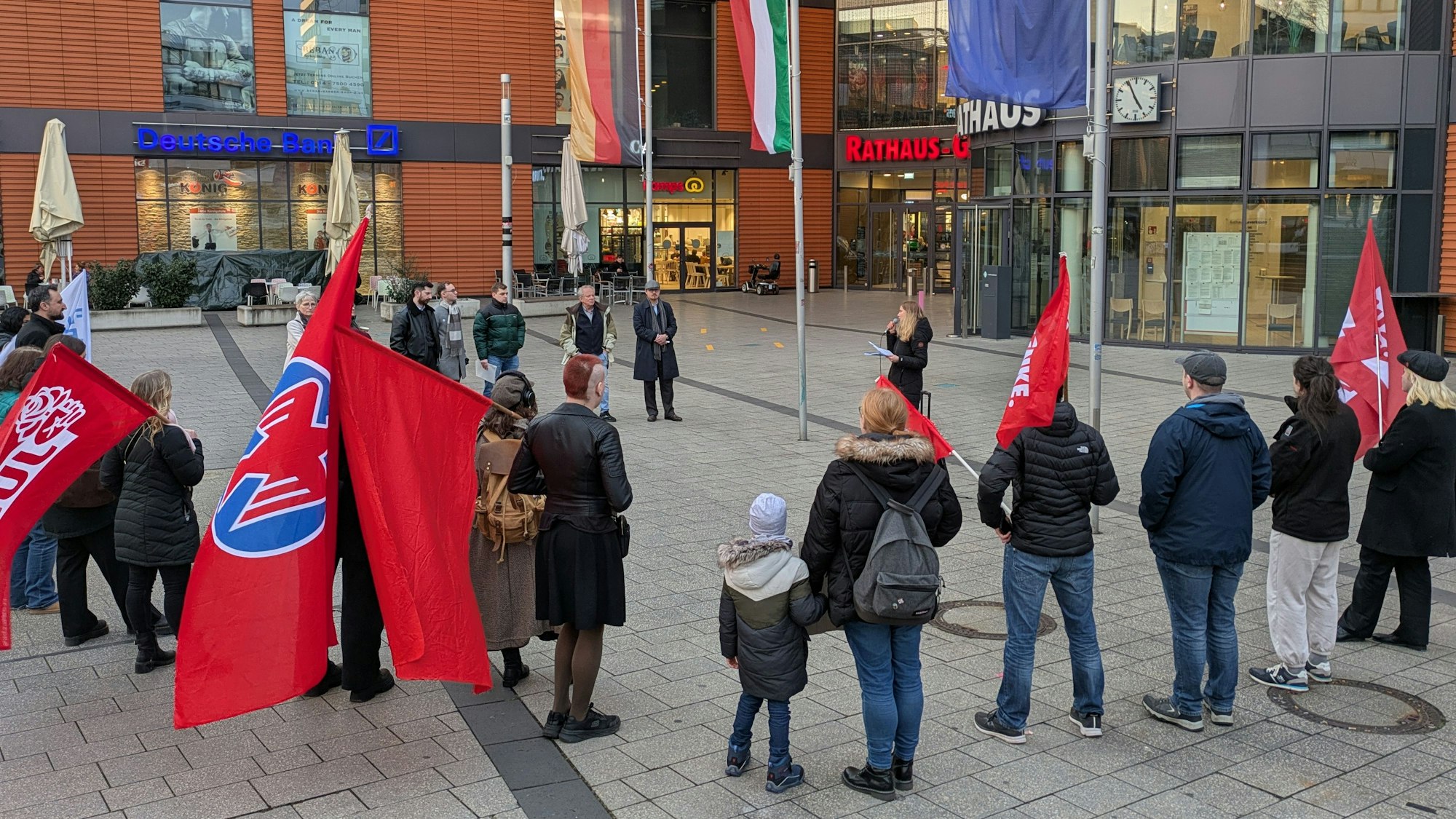 Menschen stehen mit Fahnen bei einer Protestveranstaltung vor dem Rathaus in Wiesdorf.