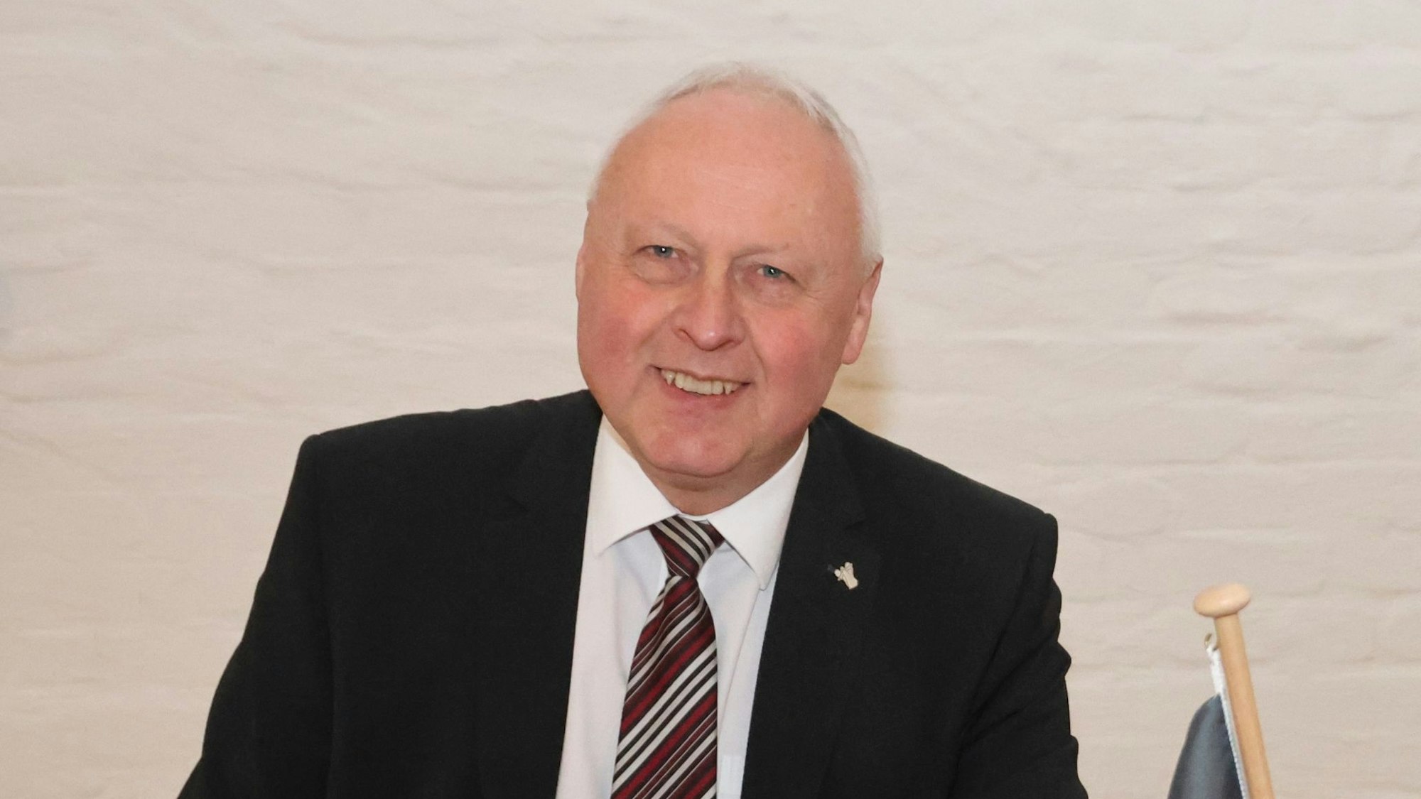 Portraitfoto von Gero Karthaus, er schaut direkt in die Kamera und trägt einen dunklen Anzug, weißes Hemd und Krawatte.