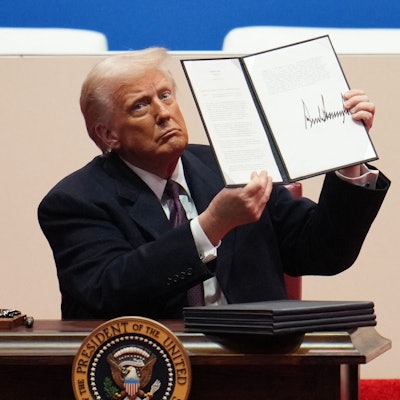 Donald Trump hält ein Dekret mit seiner Unterschrift in die Höhe.