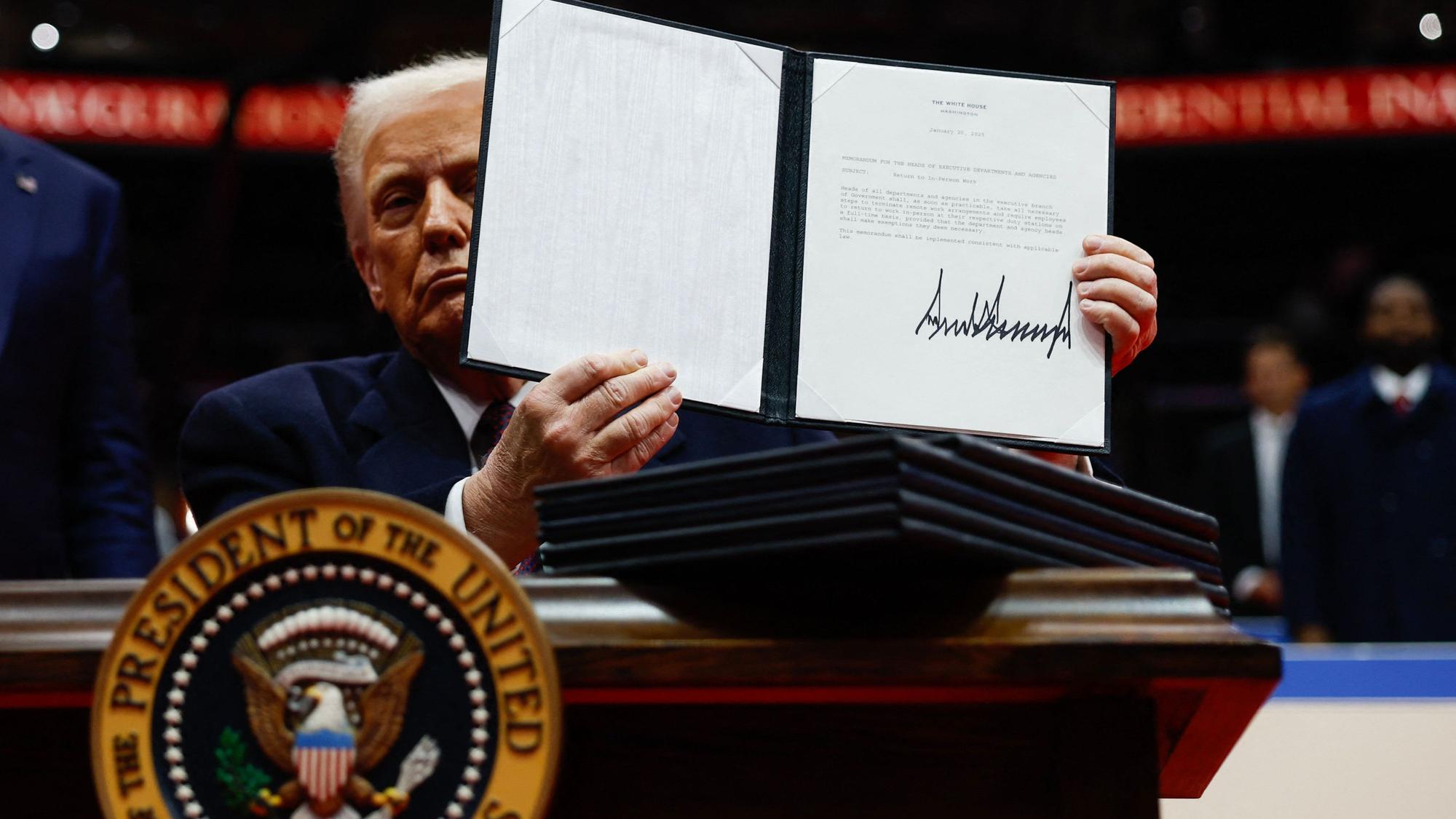 Donald Trump streckt ein unterschriebenes Papier in die Höhe.