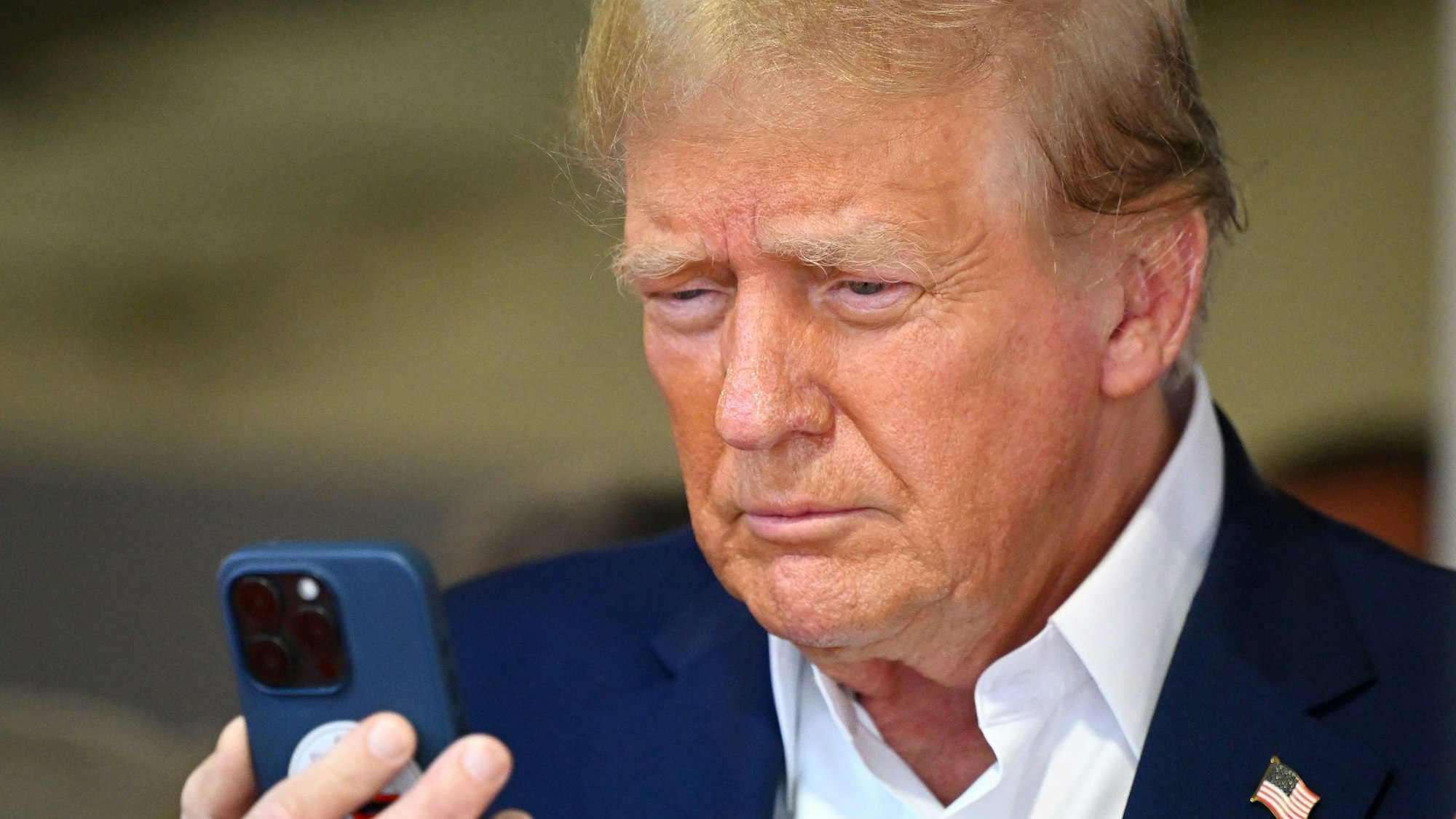 Donald Trump betrachtet einen Handy-Bildschirm. Telefonate mit dem US-Präsidenten gelten mitunter als Herausforderung. (Archivbild)