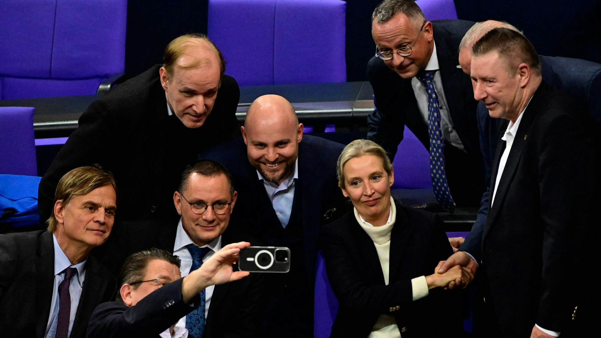 Members of the far-right Alternative for Germany (AfD) party including AfD co-leaders Alice Weidel (2ndR) and Tino Chrupalla (2ndL) take a group picture with a mobile phone as they celebrate after a vote during a session at the Bundestag, lower house of parliament, on January 29, 2025 in Berlin. (Photo by John MACDOUGALL / AFP)