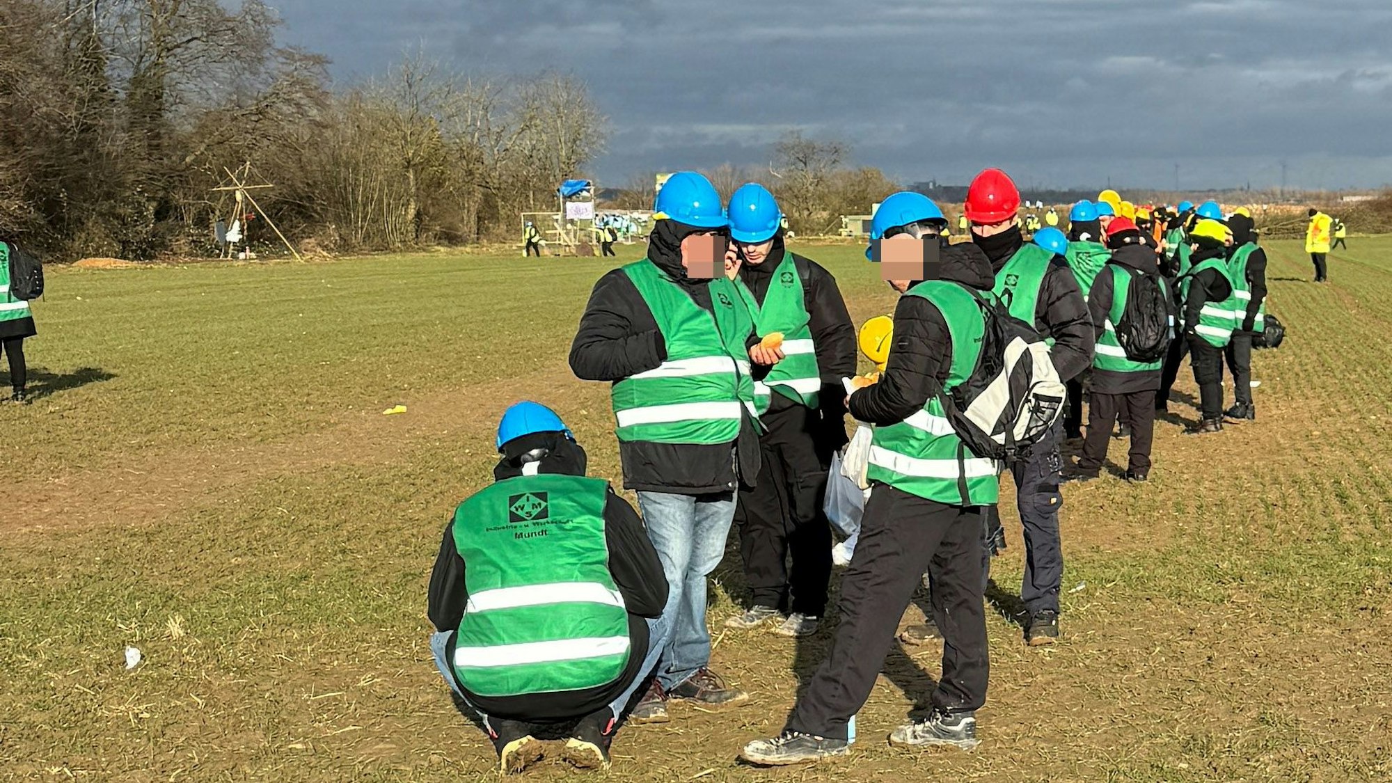 Das Bild zeigt mehrere Mitarbeiter eines Sicherheitsdienstes auf einem Feld am Sündenwäldchens in Kerpen.