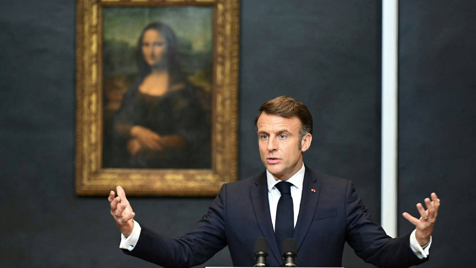 28.01.2025, Frankreich, Paris: Der französische Präsident Emmanuel Macron hält eine Rede, um eine mehrjährige Überholung und langfristige Investitionen zur Modernisierung des Louvre anzukündigen. Er steht neben Leonardo da Vincis Gemälde der Mona Lisa.