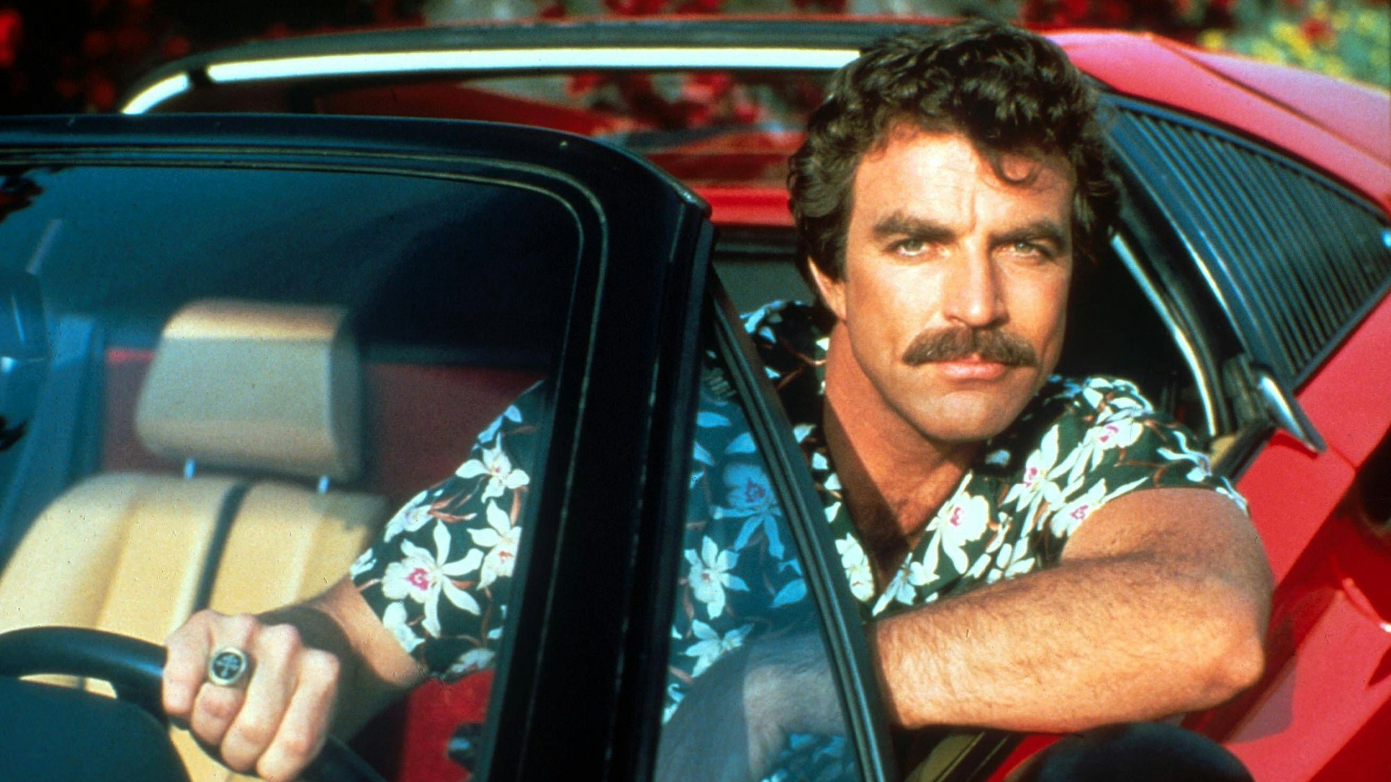 Tom Selleck sitzt in seiner Rolle als Thomas Magnum im Auto.