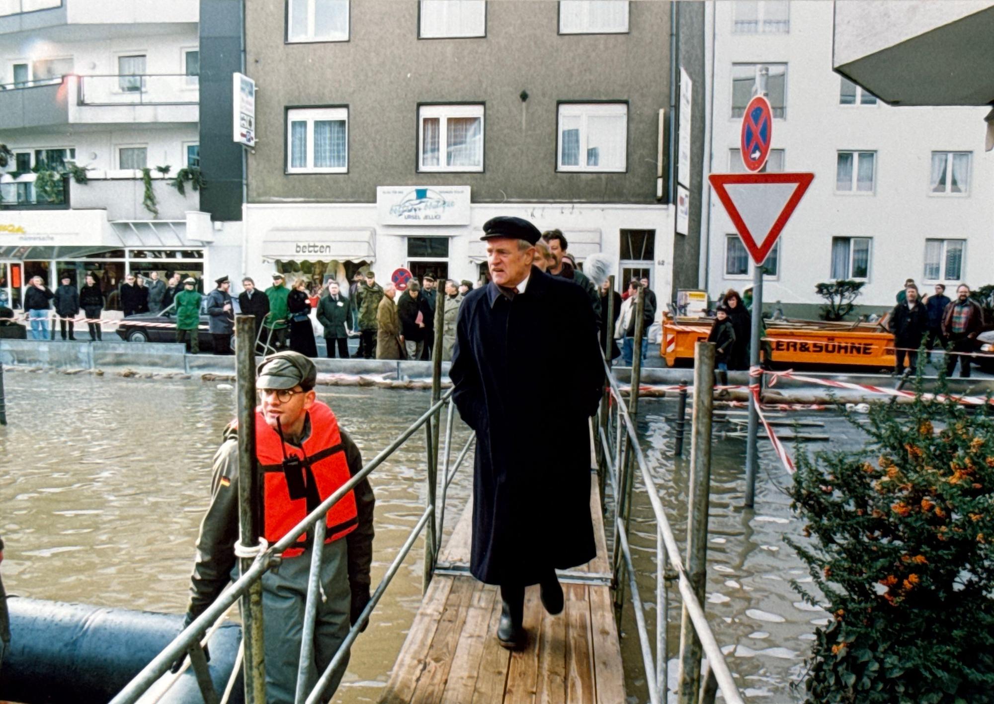 30.01.1995, Köln: Hochwasser. Ministerpräsident Johannes Rau geht über einen mobilen Steg an der Rodenkirchener Hauptstraße (im Hintergrund Hausnummer 62) während daneben ein Soldat der Bundeswehr mit einer Rettungsweste im Wasser steht. Foto: Walter Schiestel