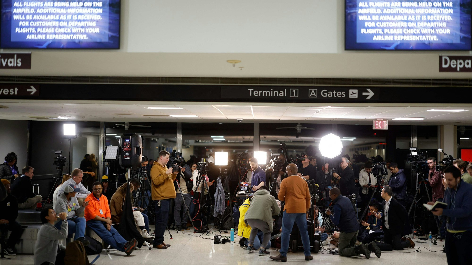 Information screens in Reagan National Airport display emergency instructions as journalists wait for a media briefing after a plane crashed into the Potomac River outside Washington, DC, January 29, 202. A regional jet from Kansas crashed into Washington's Potomac River after colliding mid-air with a military helicopter near Reagan National Airport, officials said January 29, prompting a major emergency response and grounding all flights. (Photo by Ting Shen / AFP)