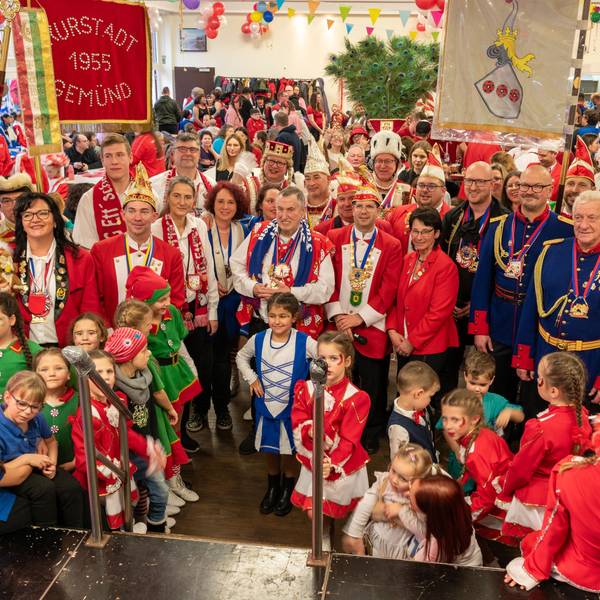 Eine große Gruppe verkleideter Karnevalisten steht mit Fahnen vor eine Bühne. Mittendrin: Schleidens Bürgermeister Ingo Pfennings.