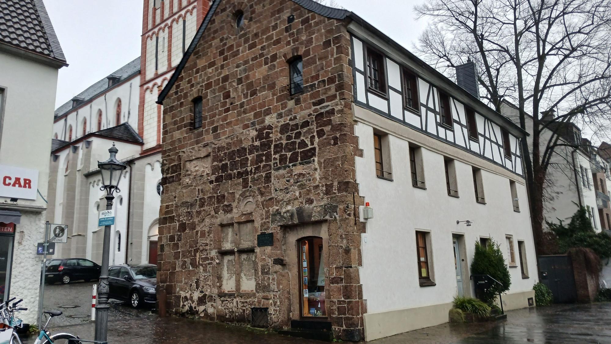 Ein altes Haus an einer Kirche.