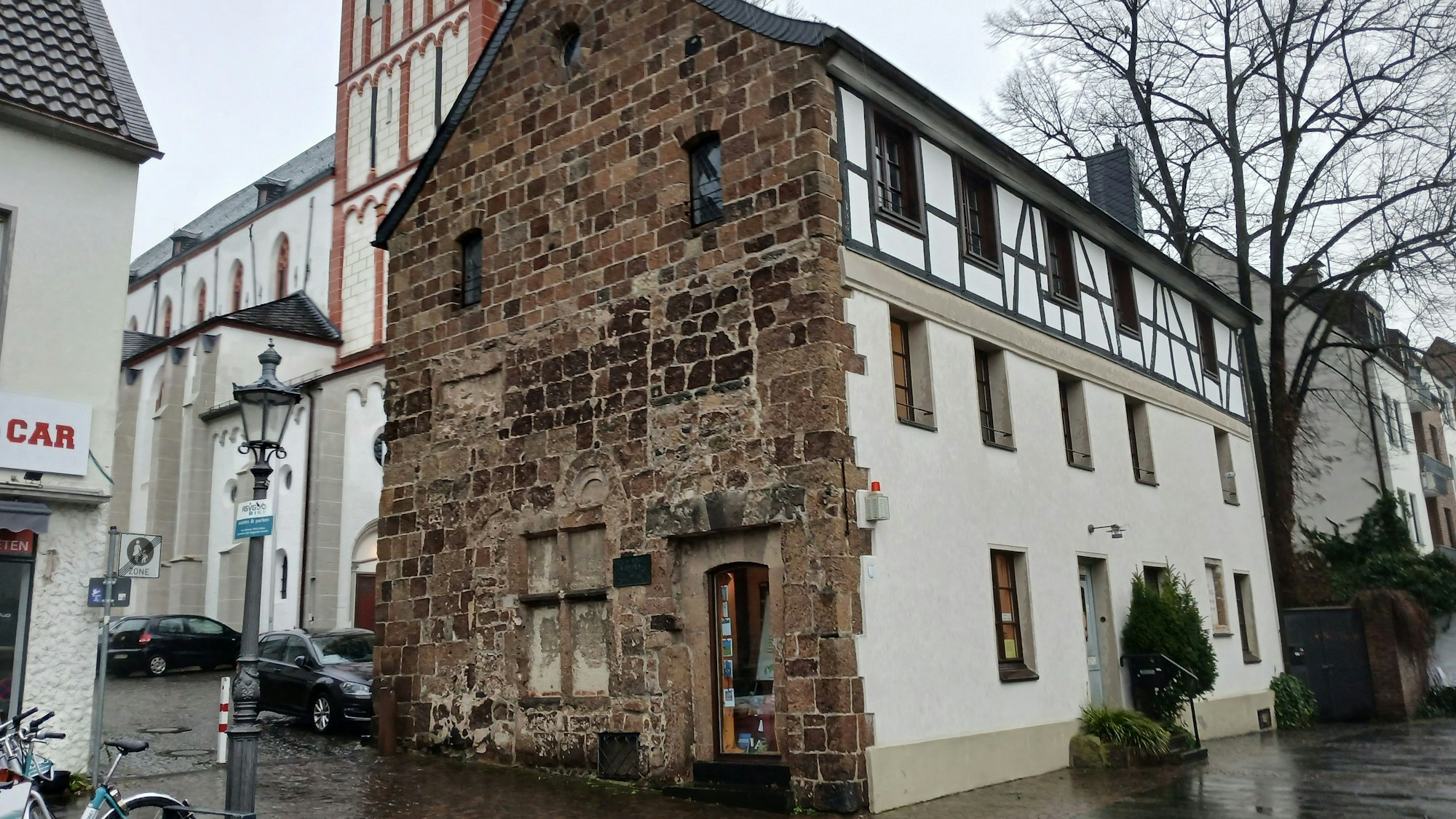 Ein altes Haus an einer Kirche.