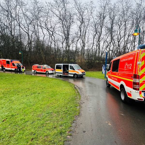 Einsatzfahrzeuge der Feuerwehr Bonn auf einem Weg. Im Hintergrund Bäume, links eine Wiese.