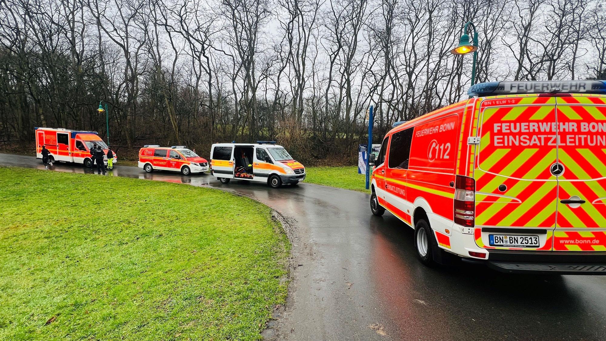 Einsatzfahrzeuge der Feuerwehr Bonn auf einem Weg. Im Hintergrund Bäume, links eine Wiese.