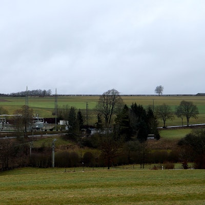 Nicht weit von einem abfallenden Gelände liegt ein Umspannwerk mit einem Betriebsgebäude.
