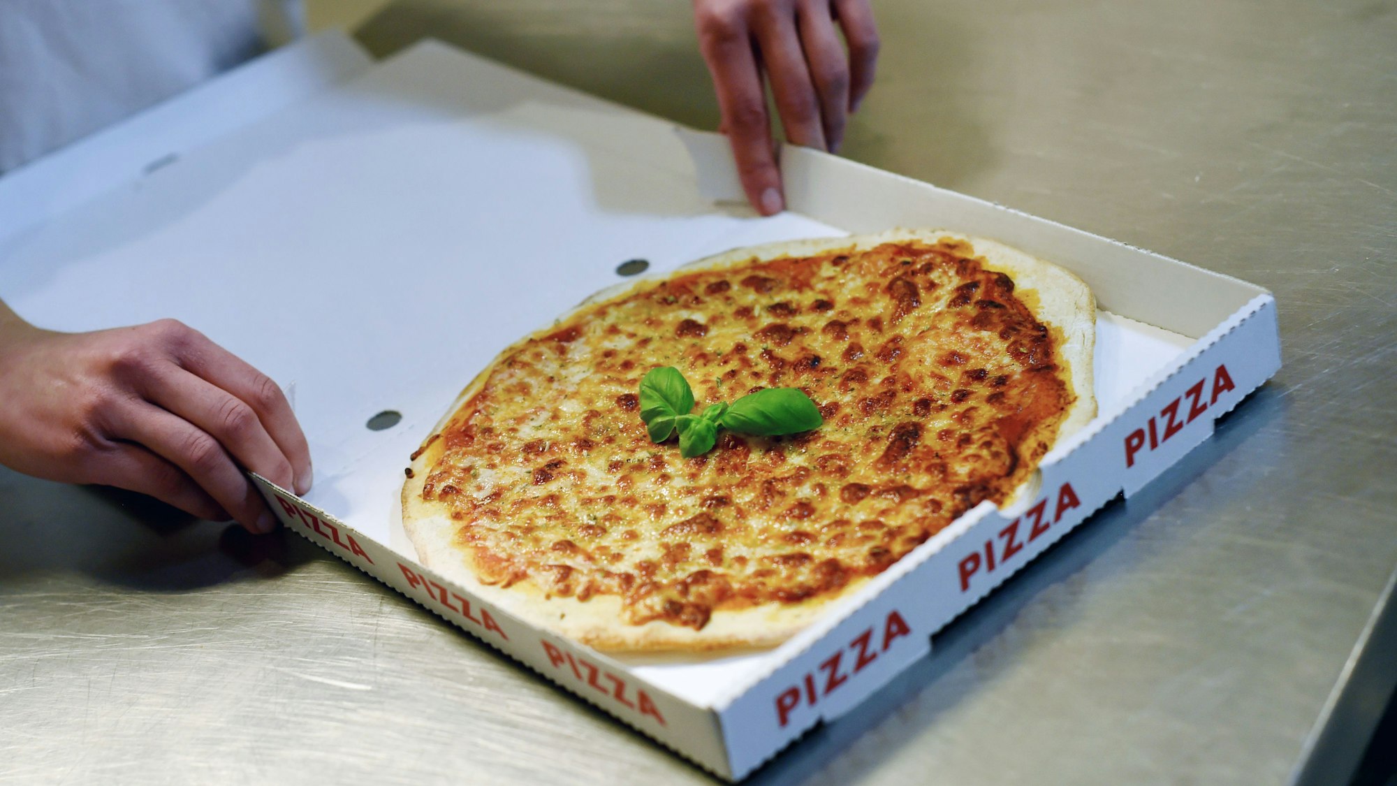 Das Foto zeigt eine Pizza im Karton.