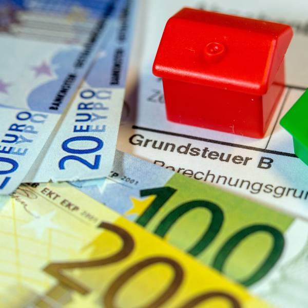 Zwei Spielzeughäuser und die Nachbildung von Euro-Geldscheinen liegen auf einem Abgabenbescheid für die Entrichtung der Grundsteuer. (Symbolbild)