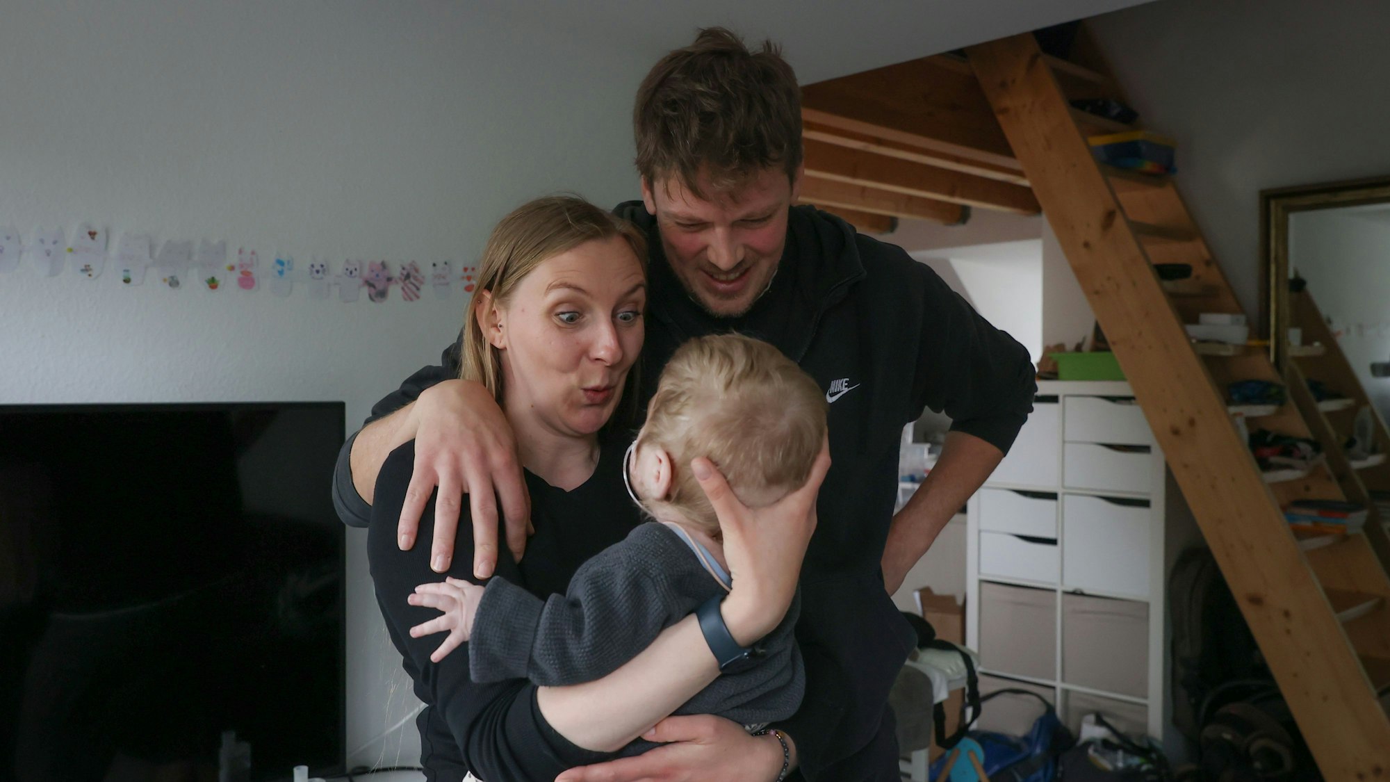 Mutter Leuschen hat ihre Tochter im Arm, der Vater hat den Arm um ihre Schulter gelegt.
