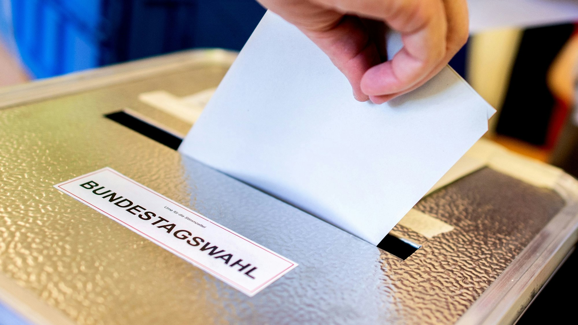 Ein Wähler wirft in einem Wahllokal seinen Stimmzettel für die Bundestagswahl in eine Wahlurne.