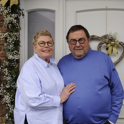 Ein Ehepaar steht vor einer geschmückten Haustür.