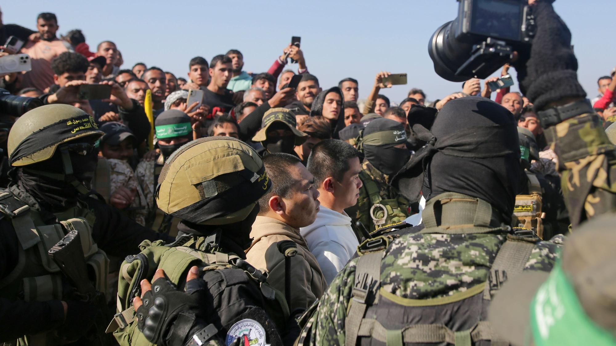 Zwei thailändische Männer, die seit dem 7. Oktober 2023 von der Hamas in Gaza als Geiseln gehalten wurden, werden von Hamas-Kämpfern eskortiert, als sie dem Roten Kreuz übergeben werden.