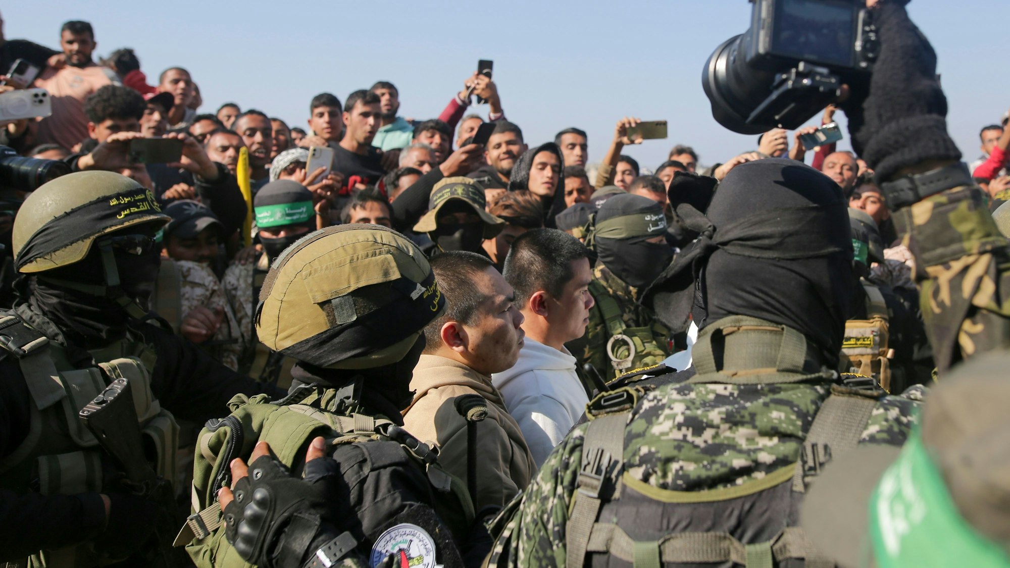 Zwei thailändische Männer, die seit dem 7. Oktober 2023 von der Hamas in Gaza als Geiseln gehalten wurden, werden von Hamas-Kämpfern eskortiert, als sie dem Roten Kreuz übergeben werden.