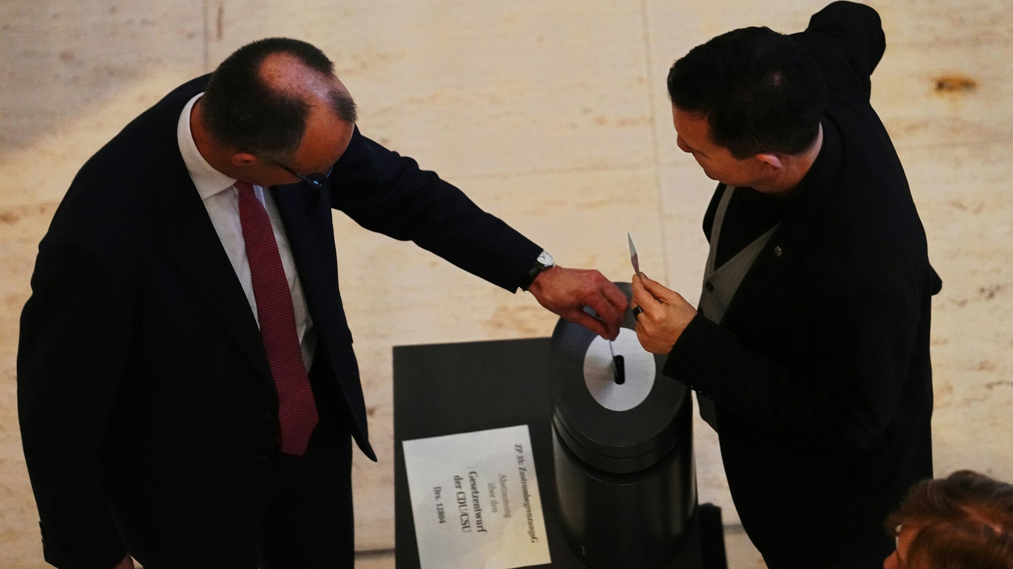Friedrich Merz (l), CDU-Bundesvorsitzender und CDU/CSU-Fraktionsvorsitzender im Bundestag, gibt bei der Abstimmung über das Zustrombegrenzungsgesetz der Union zur Eindämmung der Migration im Bundestag seine Stimmkarte ab.