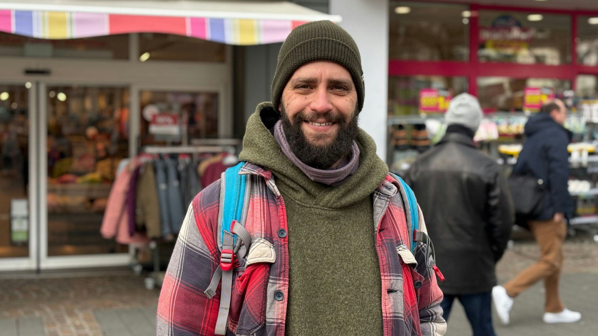 Ein Mann mittleren Alters steht in der Siegburger Fußgängerzone und lächelt.