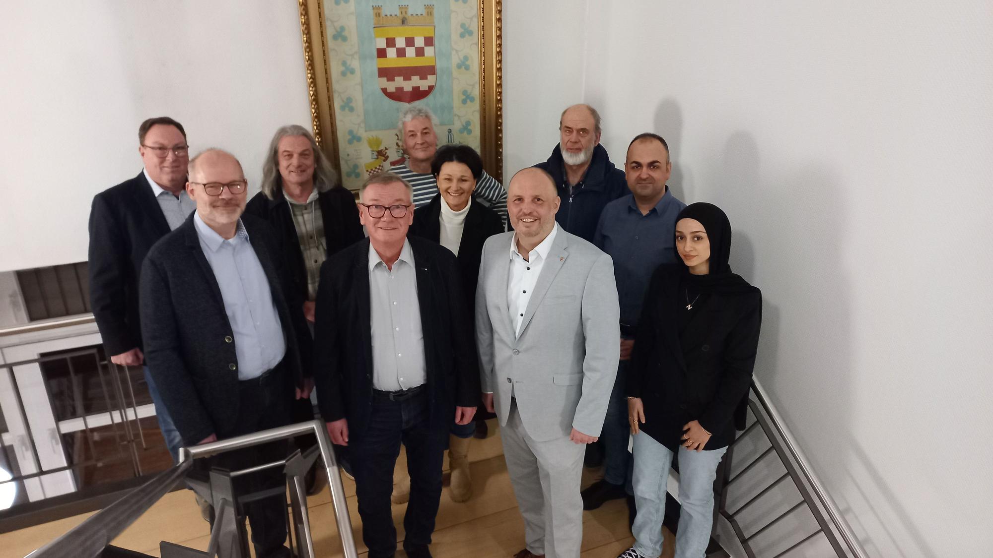 Eine Gruppe von Menschen steht vor dem Bergneustädter Stadtwappen.