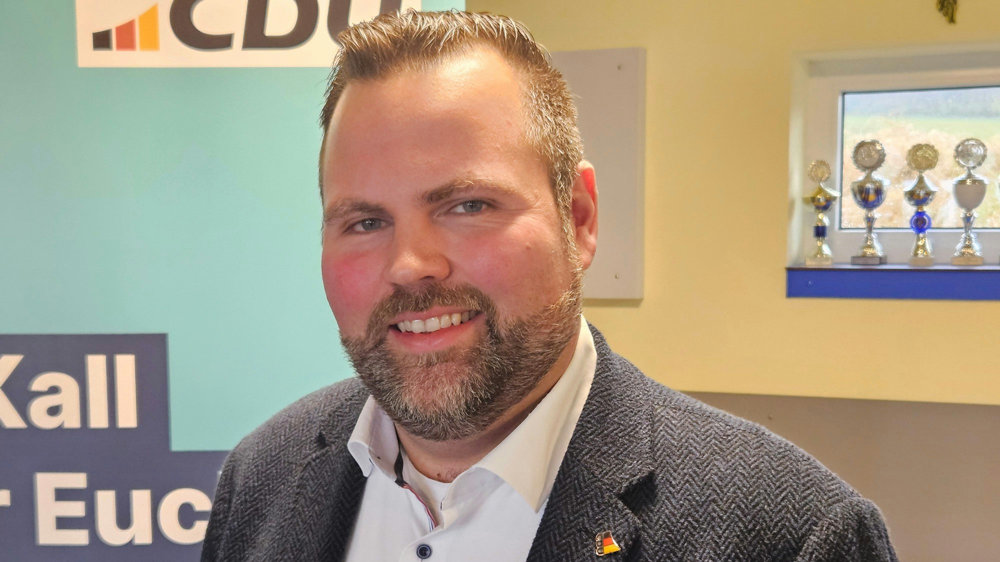 Michael Kehren steht vor einem CDU-Roll-up. Er trägt einen sauber gestutzten Bart, Sakko und ein weißes Hemd.