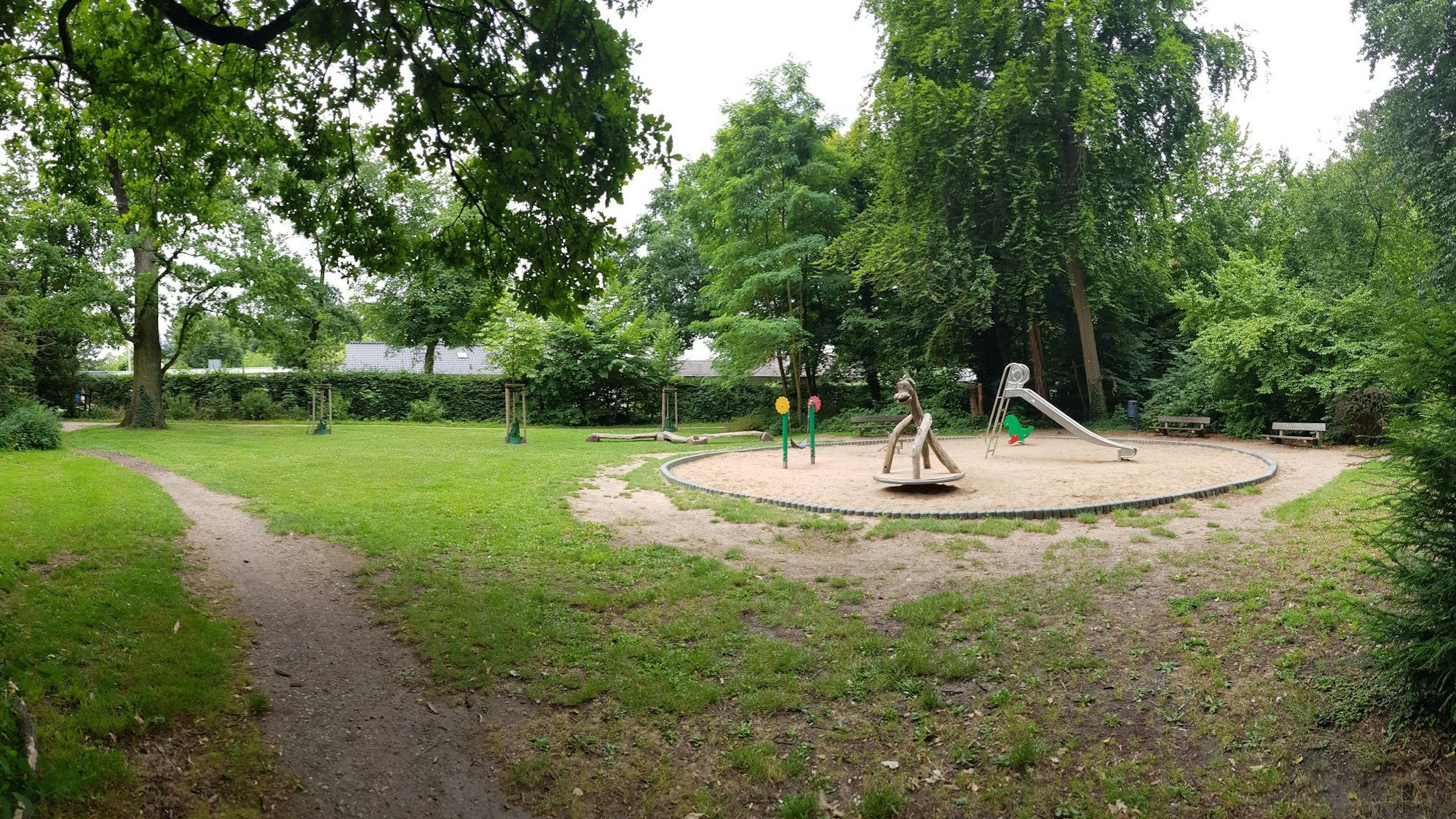 Zu sehen ist ein Spielplatz in einem grünen Park.