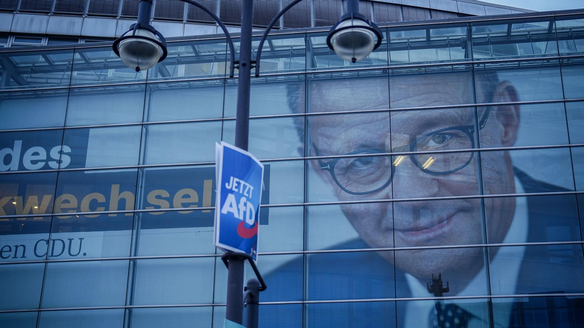 In der verglasten CDU-Parteizentrale in Berlin hängt ein riesiges Wahlplakat von Friedrich Merz. Davor hängt an einem Laternenmast ein Wahlplakat der AfD.