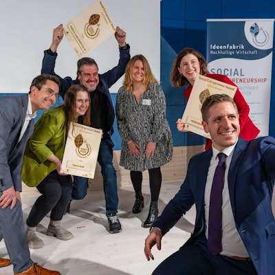 Im Vordergrund hat Landrat Markus Ramers ein Handy zum Fotografieren gezückt, während die drei Erstplatzierten juveld in die kamera schauen.