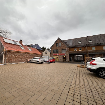 Auf einem großen Parkplatz stehen wenige Autos.