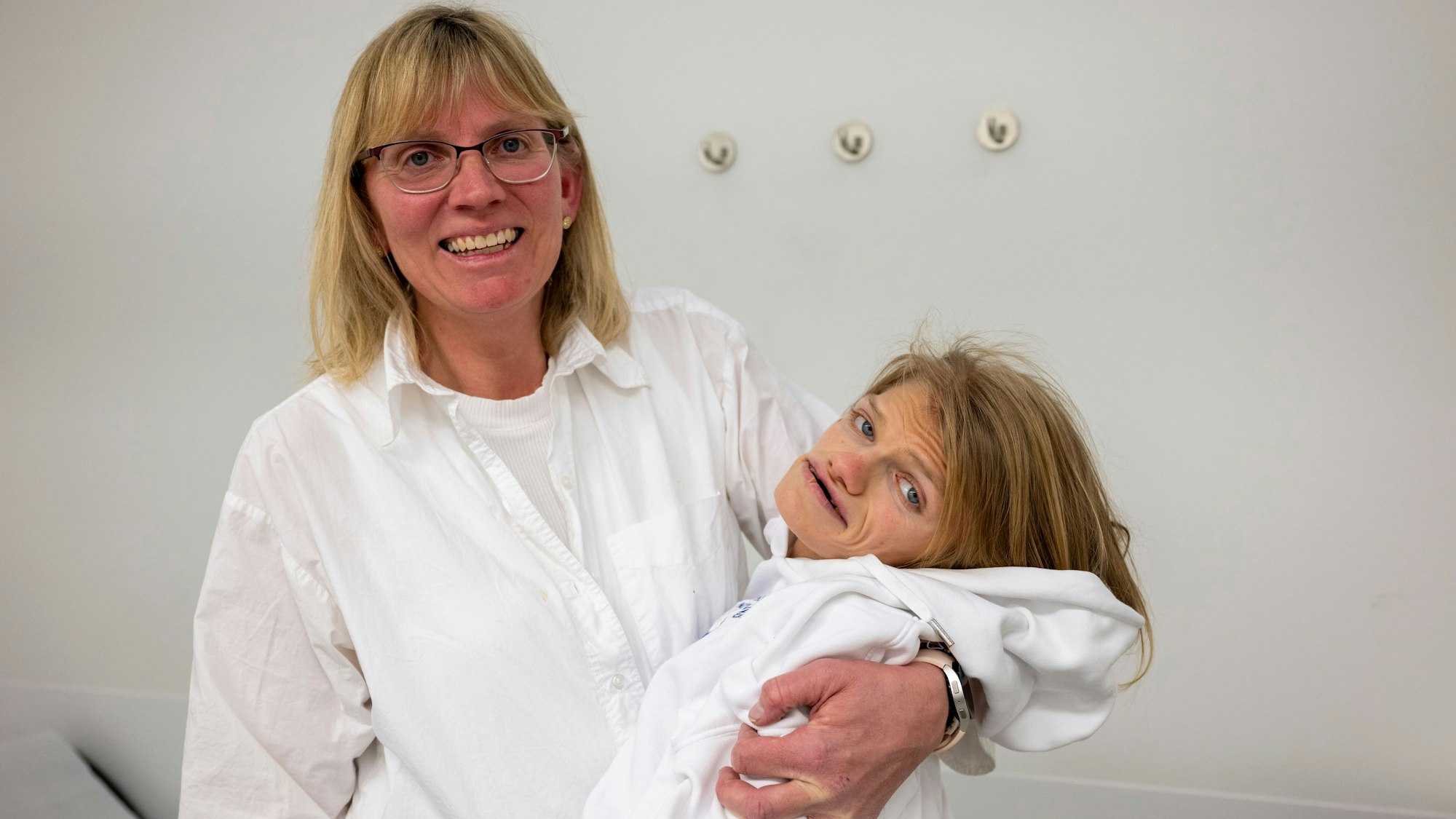 Ute Schneider hält ihre schwerbehinderte Tochter Laura im Arm und lacht in die Kamera.