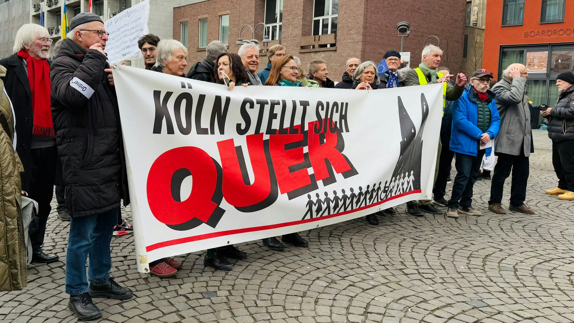 Rund 20 Menschen halten auf dem Alter Markt ein Banner mit dem Schriftzug „Köln stellt sich quer“